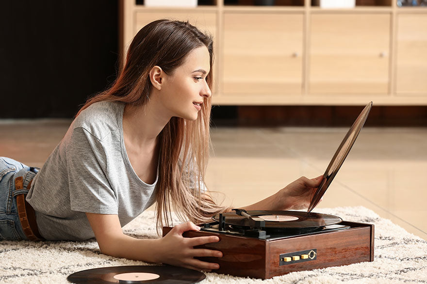 Young woman with old record player and vinyl discs at home